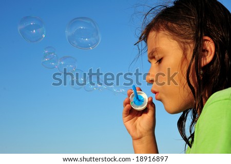 Little girl blowing soap bubbles, close up