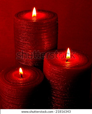 Three burning red candles on red background