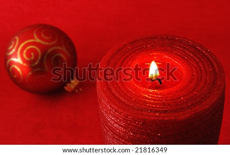 Red candle and christmas ornament on red background - selective focus