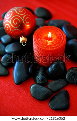 Red candle a christmas ornament on black stones