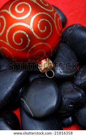 Red christmas ornament on black stones - close up