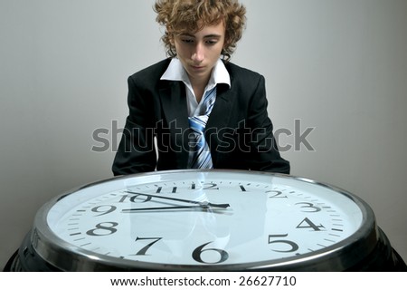 Young businessman looking at clock, deadline concept