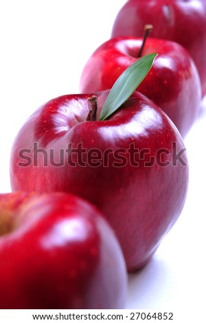 Row of four red apples on white background, selective focus on second apple