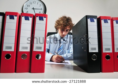 Young businessman standing at desk behind a stack of folders