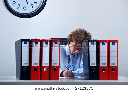 Young businessman standing at desk behind a stack of folders