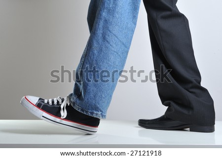 Mans legs wearing jeans and sneaker on a leg and suit on the other