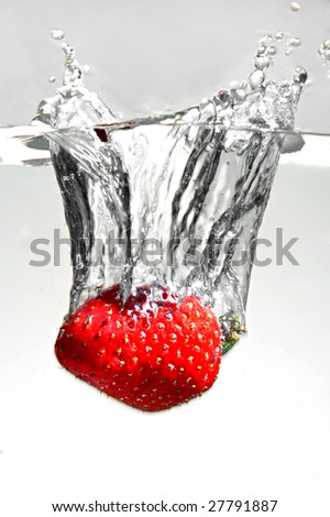 Strawberry falling in water, close up