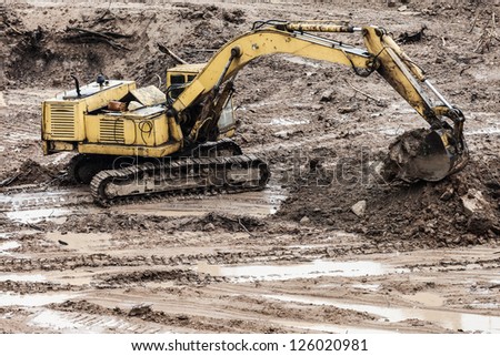 Old rusty earth digging excavator machine working at building construction site