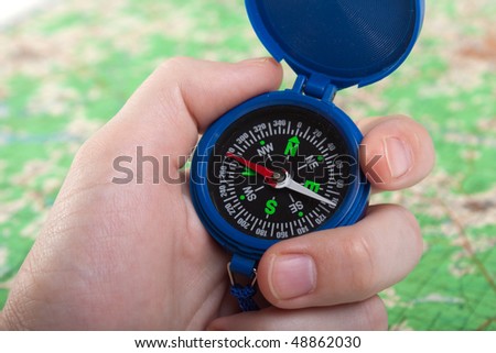 Hand holding travel north direction compass on map