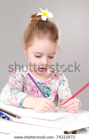 Funny little girl drawing with colored pencils