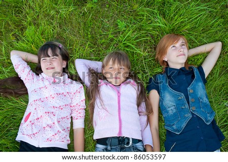 Three girls lying on meadow green grass watching the sky