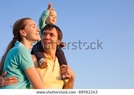 young happy family having fun outdoors with blue sky in background