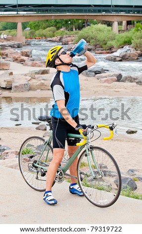 Mature cyclist takes a break in a city park by the river