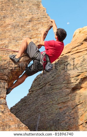 Man climbing a rock face with the moon in the sky