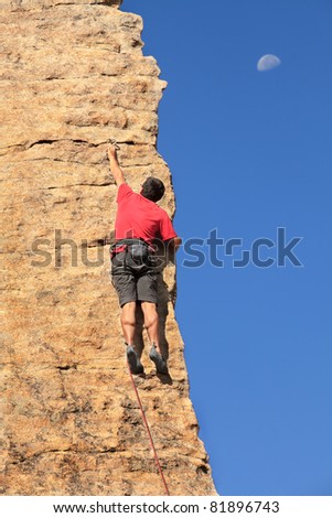 Man climbing a rock face with the moon