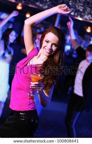 Young woman having fun and dancing at night club disco