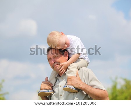little boy sitting on the shoulders of his grandfather