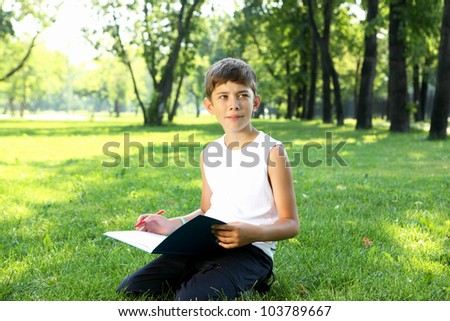 Portrait of a boy sitting with a book in the park