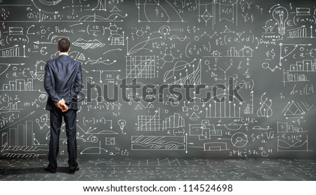 Business Person Standing Against The Blackboard With A Lot Of Data Written On It