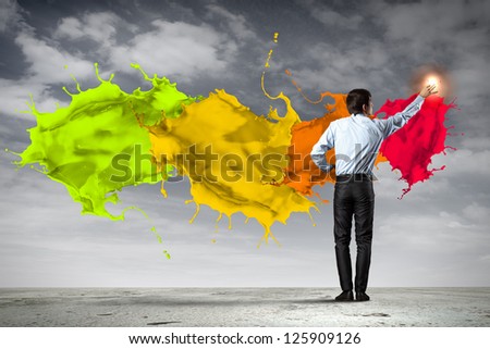 young man standing with back painting splashes with fingers