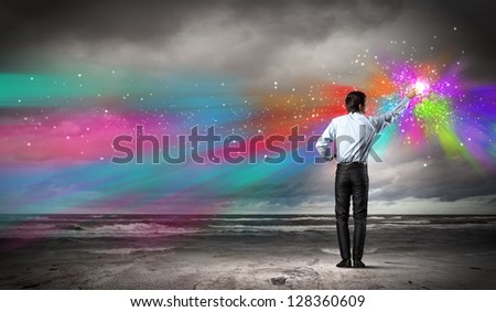 young man standing with back painting splashes with fingers