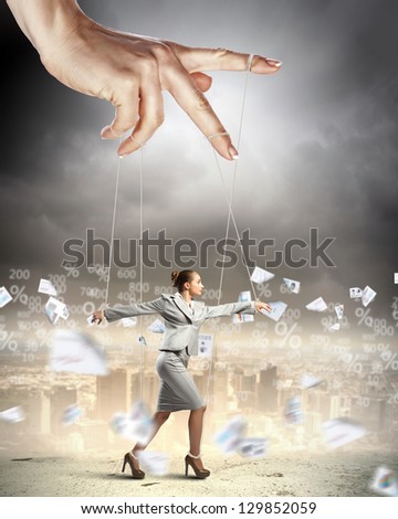 Businesswoman marionette on ropes controlled by puppeteer against documents picture