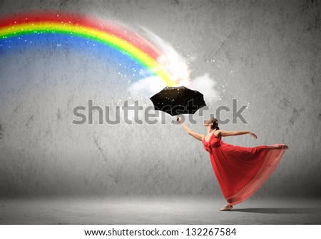 ballet dancer in flying satin dress with umbrella and a rainbow
