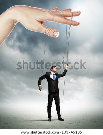 Businessman marionette on ropes controlled by puppeteer