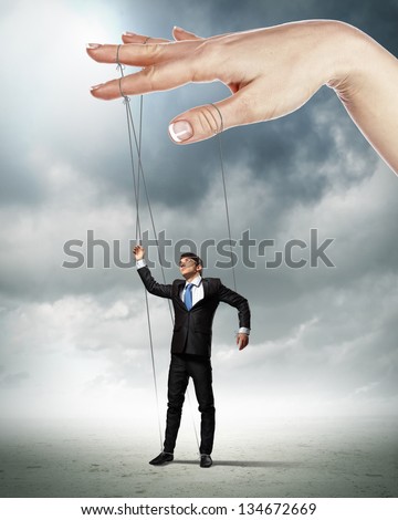 Businessman marionette on ropes controlled by puppeteer