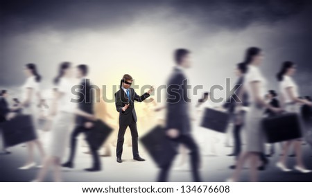 Image of businessman in blindfold walking among group of people