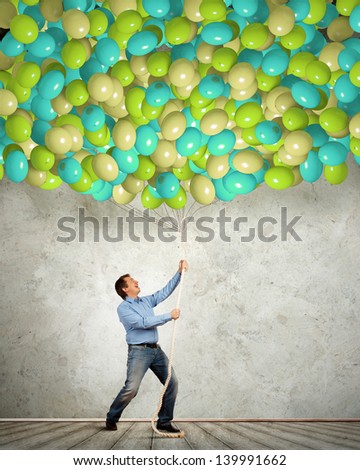 Image of adult man pulling rope with bunch of colorful balloons