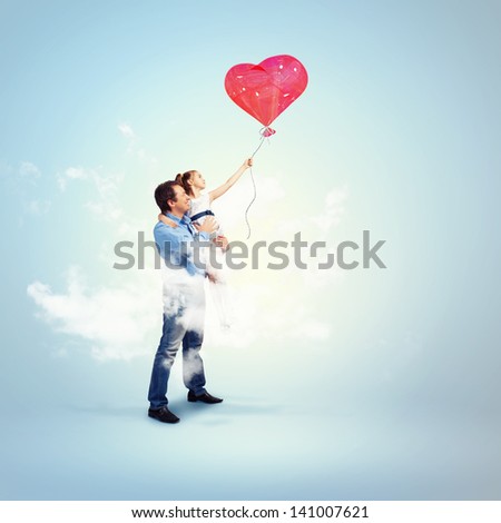Image of happy father holding his daughter and a red heart baloon