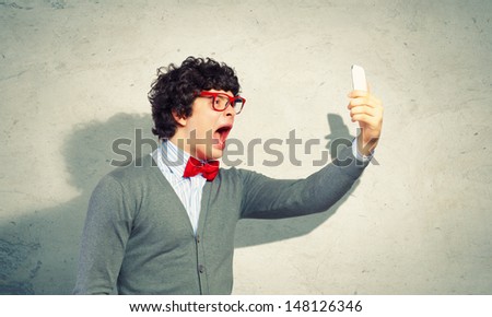 Young businessman with a red tie shouting furiously at his mobile phone