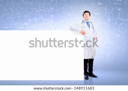 Young male doctor leaning upon blank banner. Place for text