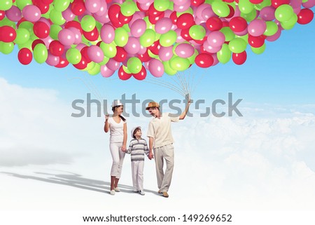 Happy young family walking holding bunch of colorful balloons