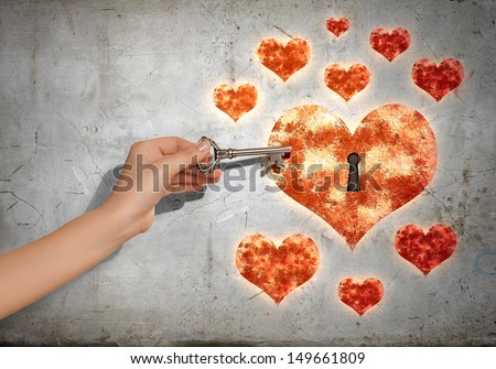 Close up of human hand with key opening heart