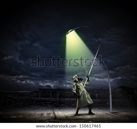 Man in gas mask and camouflage standing under street light
