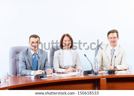 Image of three businesspeople sitting at table at conference