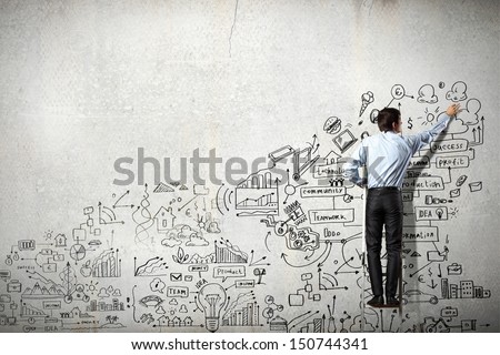 Back view of businessman drawing sketch on wall Back view of businessman drawing sketch on wall