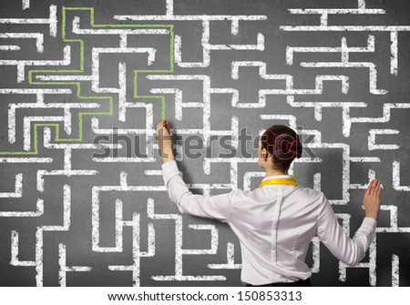 Back view image of young businesswoman trying to find way in labyrinth