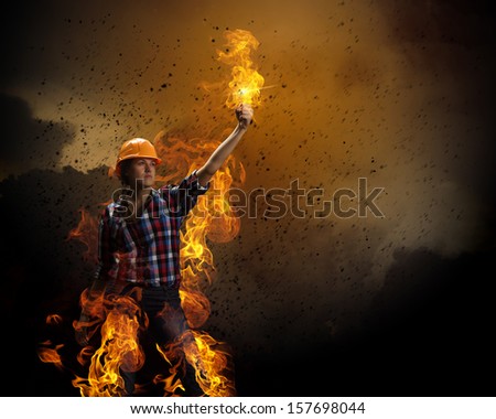 Image of woman in hardhat with torch in fire flames