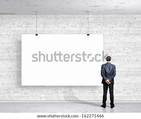 Image of businessman standing with back and looking at white banner