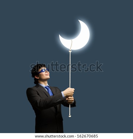 Image of young businessman in goggles looking at moon