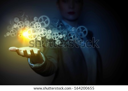 Businessperson holding gears and cogwheels in palm