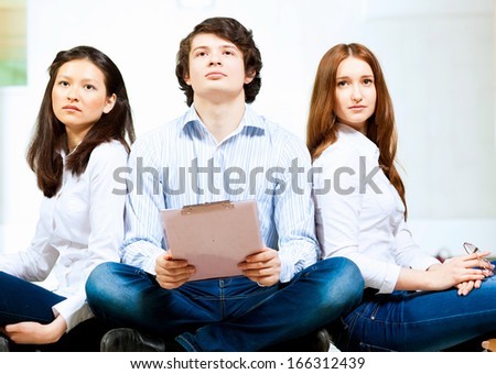 Image of three students in casual wear sitting on floor and smiling