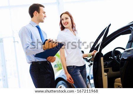 Attractive woman at car salon with consultant choosing a car