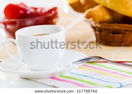 Croissants jelly and cup of coffee on breakfast table