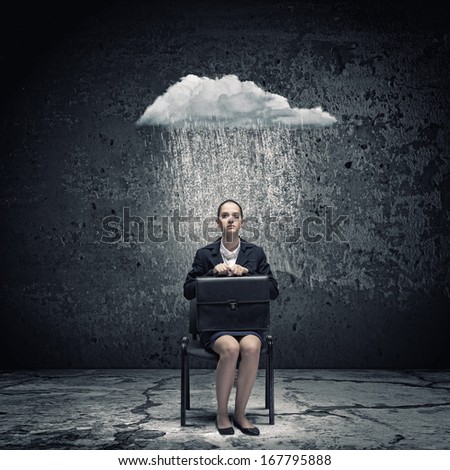Young upset businesswoman with suitcase sitting on chair