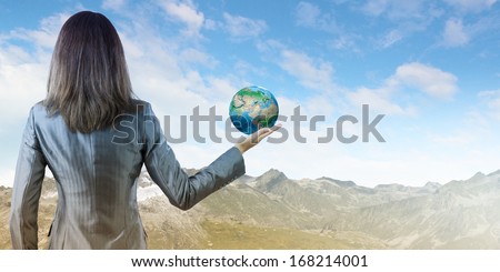 Back view of businesswoman holding earth planet in hand. Elements of this image are furnished by NASA