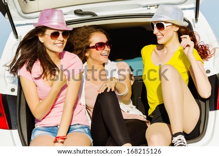 Three young pretty lady sitting in car boot